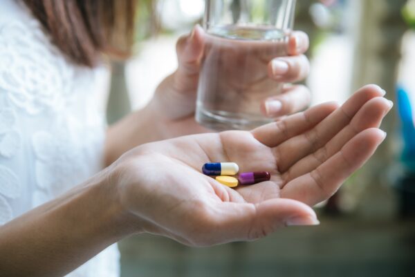 woman s hand pours medicine pills out bottle min